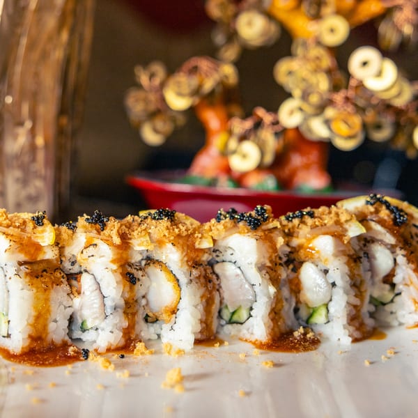 Close-up of Hot Tuna Sushi Bar and Grille's sushi roll with sauce, black caviar, and crunchy topping.