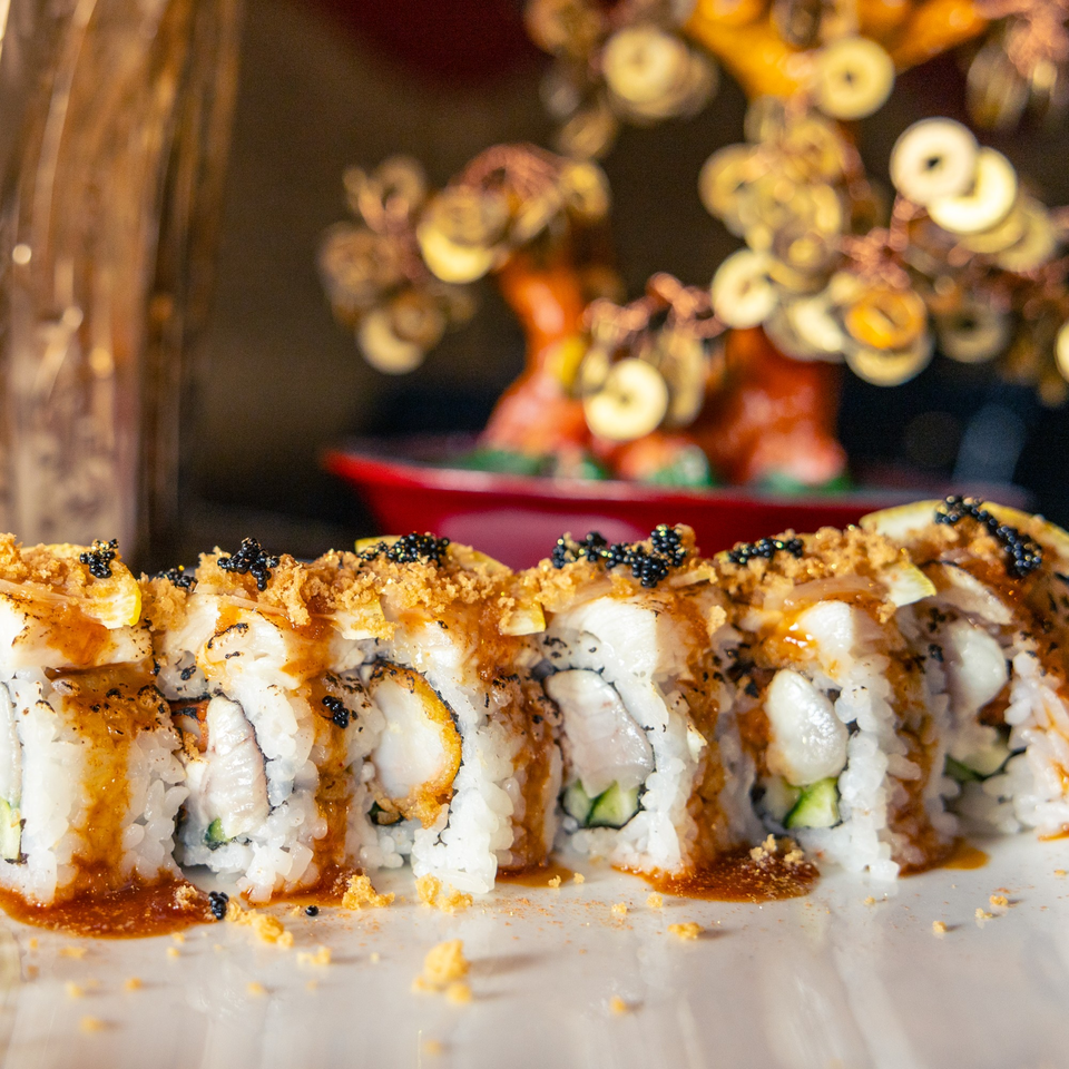 Close-up of Hot Tuna Sushi Bar and Grille's sushi roll with sauce, black caviar, and crunchy topping.