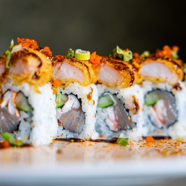 Close-up of Hot Tuna Sushi Bar and Grille's sushi rolls with crispy tempura, roe, and sauce.