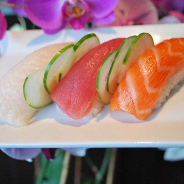 Three pieces of Hot Tuna Sushi Bar and Grille nigiri, topped with tuna, salmon, and white fish.