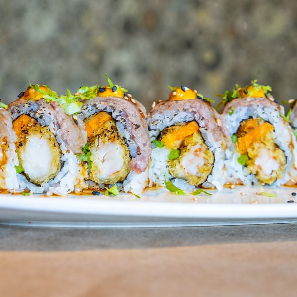 Close-up of Hot Tuna Sushi Bar and Grille's sushi rolls with shrimp tempura, beef, and sauce.